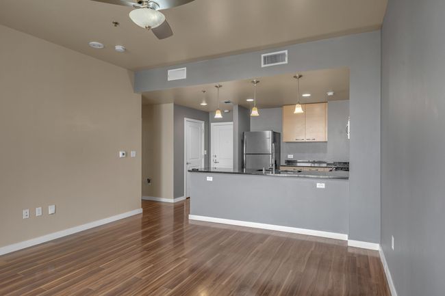 Kitchen with dark wood-style floors, visible vents, baseboards, freestanding refrigerator, and ceiling fan | Image 9