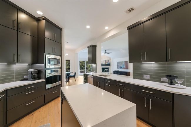 Kitchen with stainless steel appliances, a sink, light wood-style floors, recessed lighting, and light countertops | Image 8