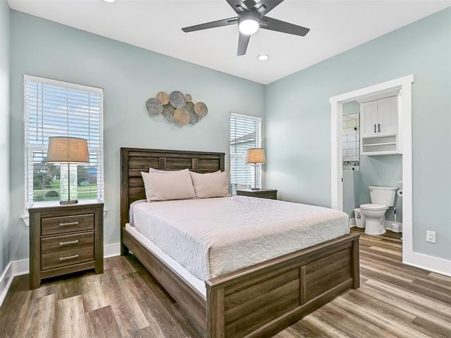 A second master suite offers additional privacy with its own en-suite bath, luxury vinyl plank flooring, ample natural light, a lighted ceiling fan, recessed lights, and stylish modern furnishings—perfect for guests or multi-family stays. | Image 20