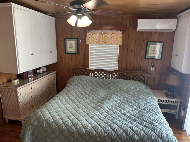 Bedroom featuring a wall mounted air conditioner, wood finished floors, wood walls, and wood ceiling | Image 21