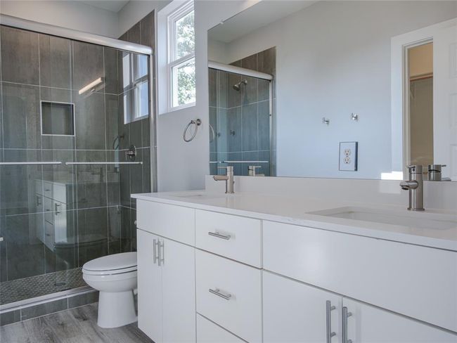 Full bathroom featuring double vanity, a stall shower, and wood finished floors | Image 18