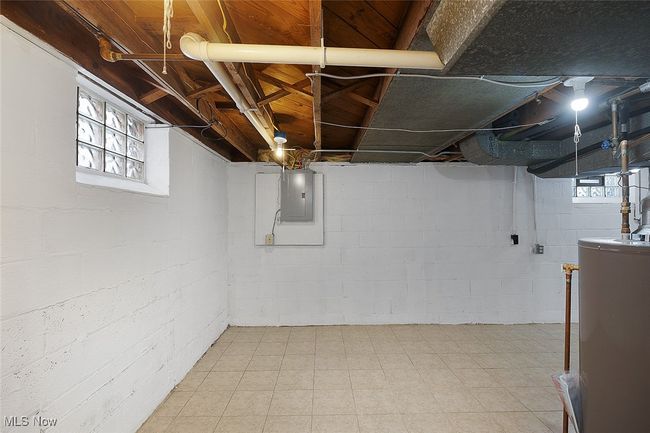Basement featuring light floors, water heater, a healthy amount of sunlight, and electric panel | Image 27