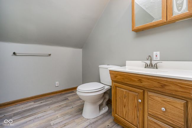 bathroom featuring baseboards, wood finished floors, toilet, vanity, and lofted ceiling | Image 21