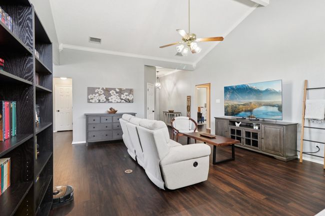 Living room with ornamental molding, ceiling fan, wood finished floors, lofted ceiling, and baseboards | Image 6