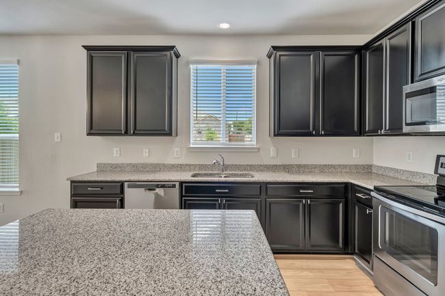Kitchen with appliances with stainless steel finishes, dark cabinets, and light wood-style flooring | Image 10