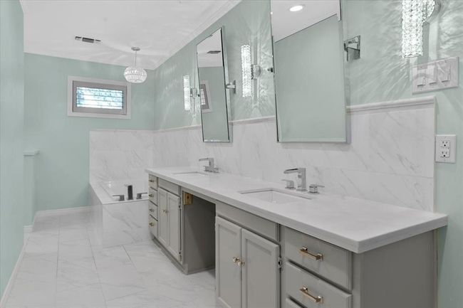 Bathroom featuring tile walls, crown molding, tile patterned floors, a tub to relax in, and dual bowl vanity | Image 12