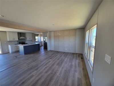 Kitchen featuring an island with sink, appliances with stainless steel finishes, hardwood / wood-style floors, wall chimney exhaust hood, and sink | Image 2