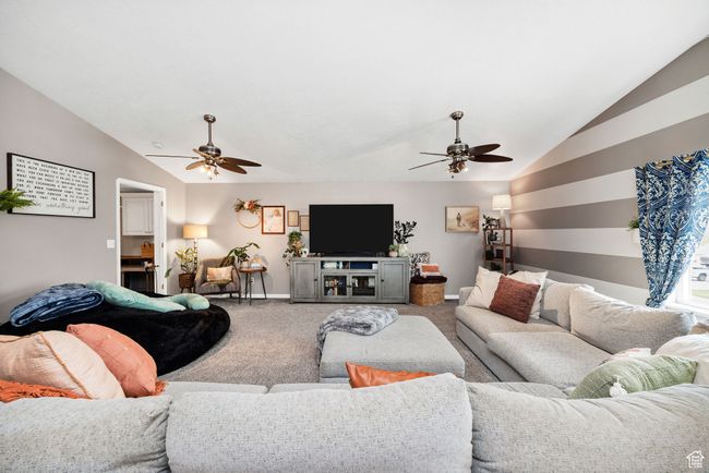 Carpeted living area featuring lofted ceiling, baseboards, and ceiling fan | Image 16