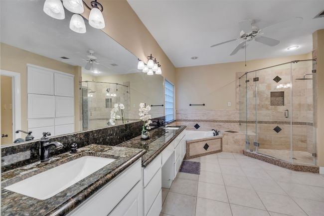 Bathroom with a ceiling fan, double vanity, a bath, and a stall shower | Image 24