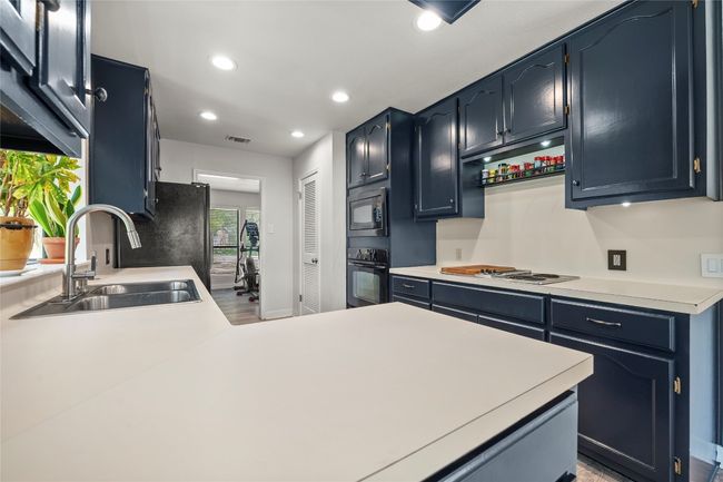 Kitchen featuring light countertops, recessed lighting, black appliances, a peninsula, and black cabinets | Image 12