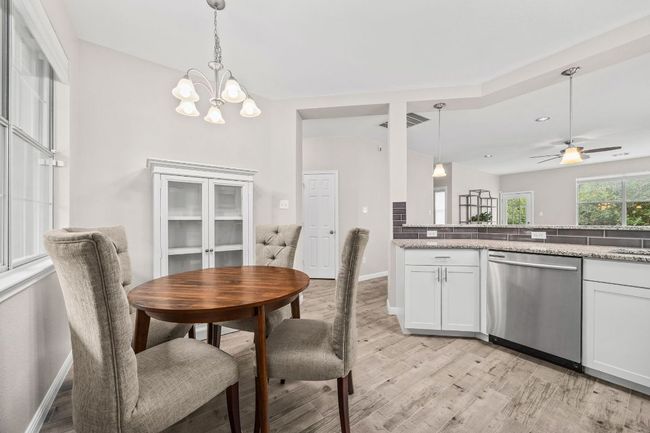 Dining area with light wood-style floors, visible vents, baseboards, recessed lighting, and ceiling fan with notable chandelier | Image 18