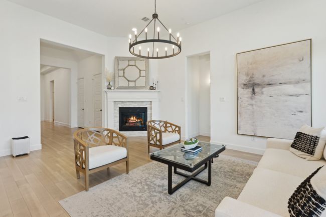 Living room featuring a chandelier, light wood-type flooring, a stone fireplace, and baseboards | Image 5