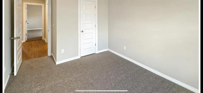 Unfurnished bedroom with dark carpet and baseboards | Image 17
