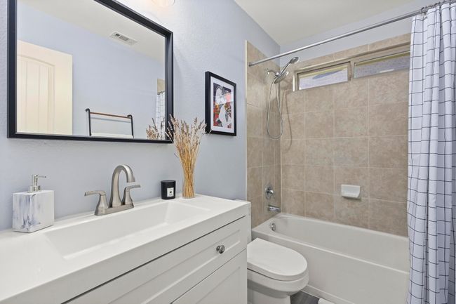 Full bath featuring shower / bath combination with curtain, toilet, vanity, and visible vents | Image 29