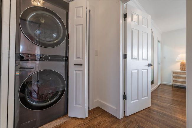 Laundry room with laundry area, dark wood-style floors, stacked washing maching and dryer, and ornamental molding | Image 21