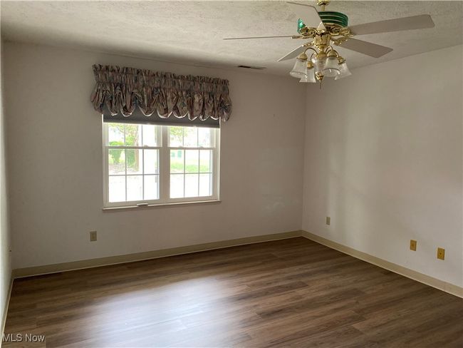 Unfurnished room featuring ceiling fan, wood finished floors, a textured ceiling, and baseboards | Image 19