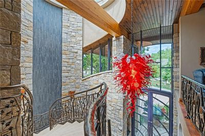 The stunning entry features a hand-blown glass chandelier, crafted by a Chihuly apprentice, on an electric chandelier lift, custom 11-foot wrought iron and glass front doors, and a 3-story, free floating staircase. | Image 3