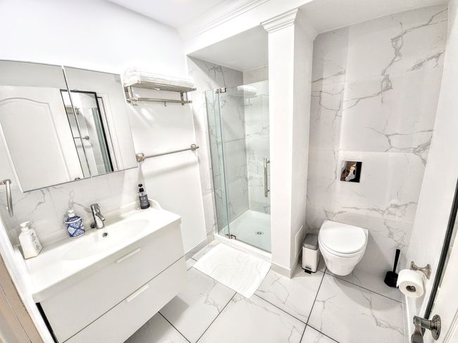 Bathroom with vanity, toilet, a marble finish shower, marble finish floors, and tile walls | Image 37
