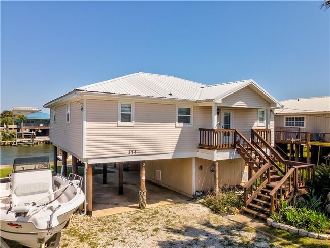 Front of house with a carport, driveway, metal roof, and stairs | Image 5