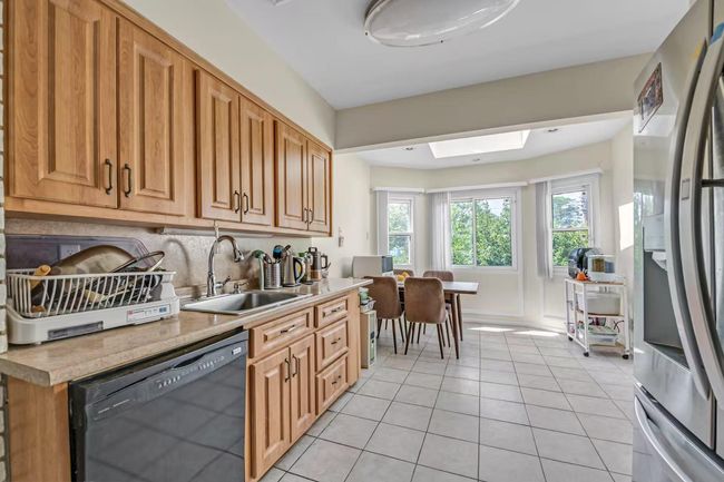 Kitchen featuring stainless steel fridge with ice dispenser, dishwasher, light tile patterned floors, a skylight, and light countertops | Image 6