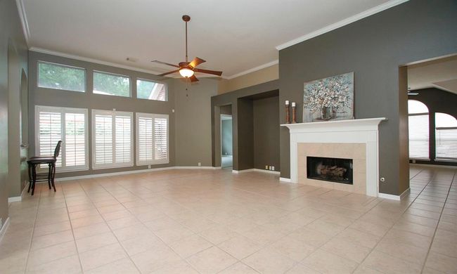 Spacious family room with tall ceiling, gas log fireplace, custom wall niche and wall-of-windows with plantation shutters. | Image 7