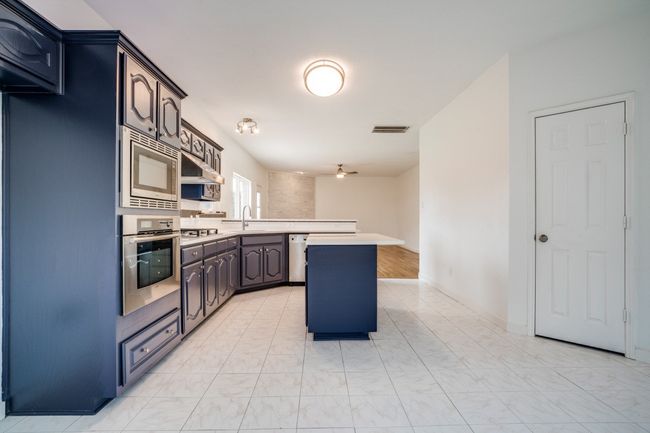 Kitchen featuring stainless steel appliances, a peninsula, a sink, light countertops, and ceiling fan | Image 11