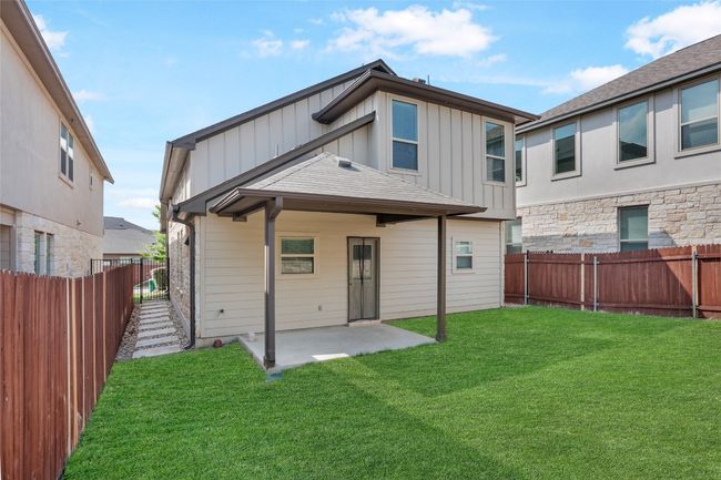 Rear view of house with board and batten siding, a lawn, a fenced backyard, and a patio area | Image 26