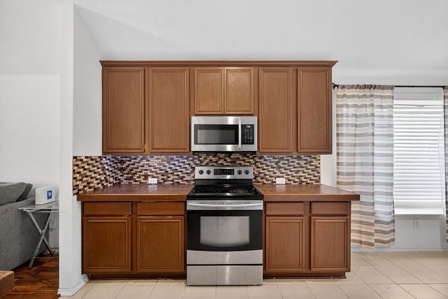 Kitchen with appliances with stainless steel finishes, dark countertops, decorative backsplash, and brown cabinetry | Image 13