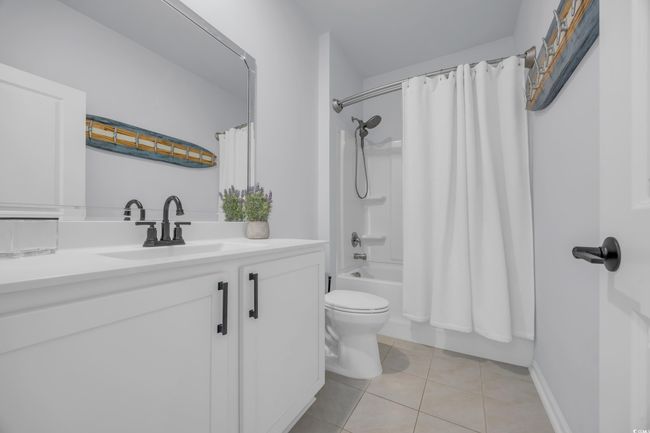 Full bath with toilet, vanity, tile patterned floors, and shower / bath combo with shower curtain | Image 9