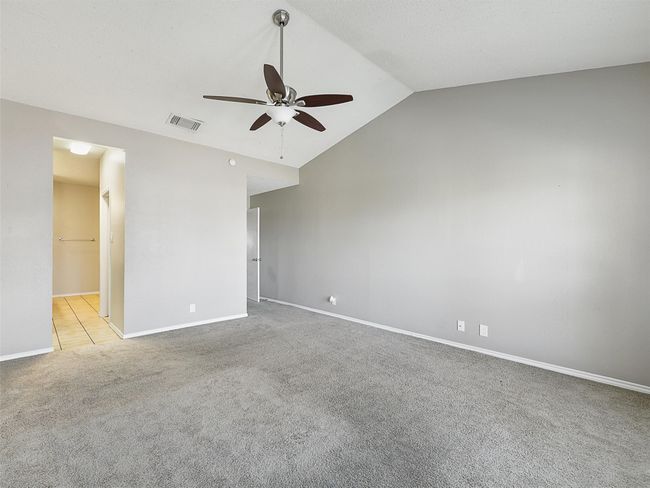 Spare room with visible vents, light carpet, lofted ceiling, baseboards, and ceiling fan | Image 23