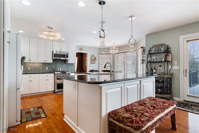 Kitchen with white cabinetry, decorative backsplash, a wealth of natural light, and stainless steel appliances. This kitchen provides a great deal of cabinet space. | Image 11