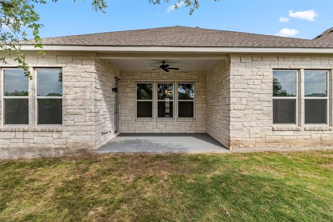 Entrance to property with ceiling fan, a lawn, and roof with shingles | Image 36