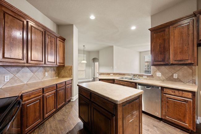 Kitchen featuring stainless steel dishwasher, arched walkways, a sink, recessed lighting, and black electric range oven | Image 15