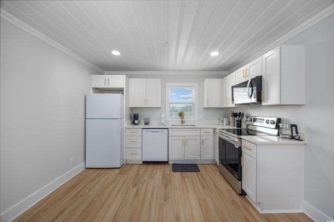 Kitchen with stainless steel appliances, a sink, crown molding, white cabinetry, and recessed lighting | Image 33