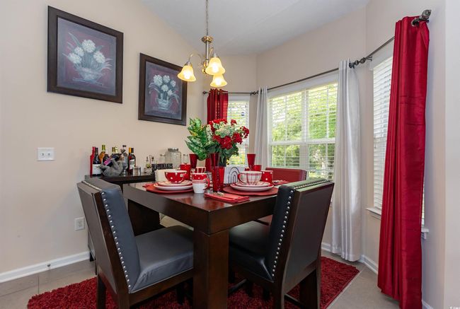 Tiled dining area with vaulted ceiling, baseboards, and an inviting chandelier | Image 8