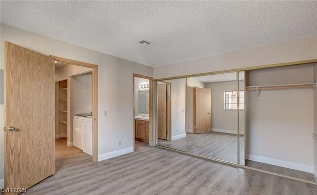 Unfurnished bedroom with light wood-style flooring, a textured ceiling, baseboards, a closet, and ensuite bathroom | Image 7