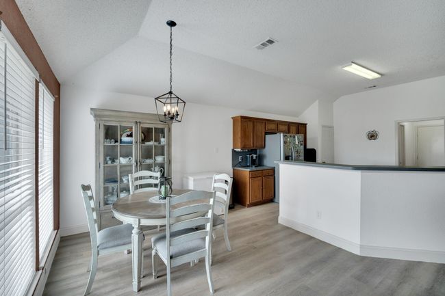 Dining area featuring vaulted ceiling, a chandelier, light wood-style floors, and a textured ceiling | Image 11