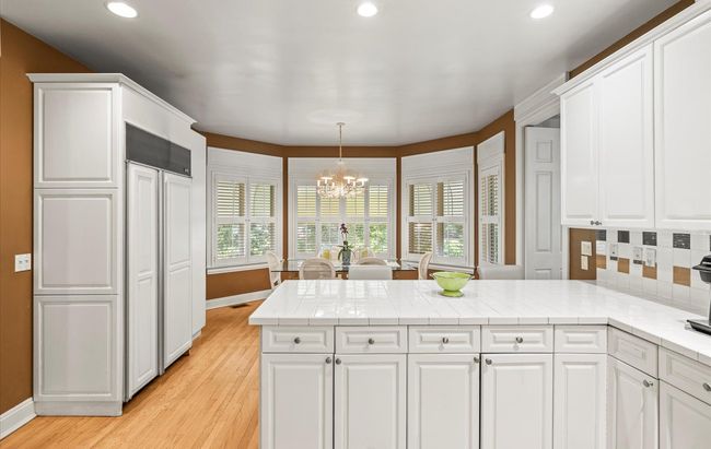 Kitchen featuring a peninsula, a chandelier, baseboards, recessed lighting, and white cabinets | Image 17