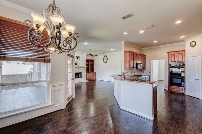 Kitchen featuring ceiling fan with notable chandelier, black appliances, backsplash, kitchen peninsula, and crown molding | Image 22