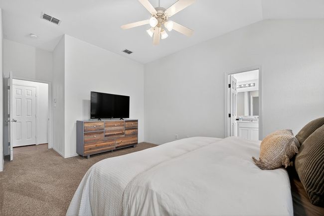 Carpeted bedroom with vaulted ceiling, a ceiling fan, and ensuite bath | Image 20