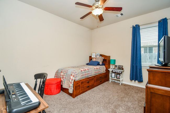 Cozy bedroom features a single bed with storage drawers, plush carpet, and a ceiling fan. | Image 23