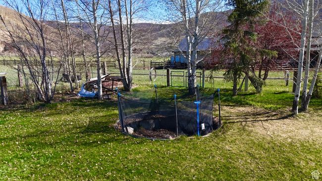 View of yard with a trampoline, a mountain view, and fence | Image 64