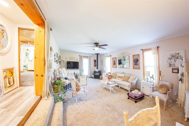 Carpeted living room with a wood stove and ceiling fan | Image 11