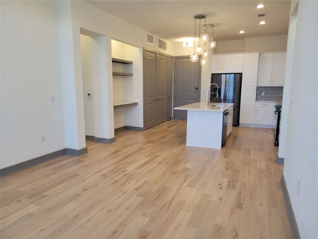 Kitchen featuring white cabinets, light wood-type flooring, baseboards, tasteful backsplash, and appliances with stainless steel finishes | Image 10