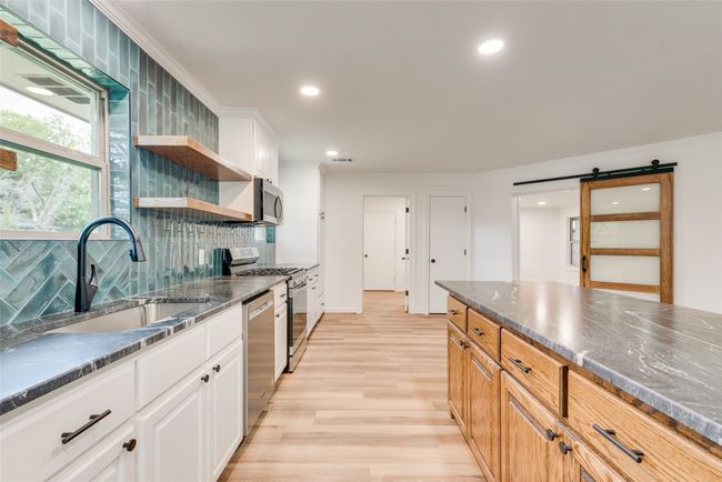 Kitchen with granite w/leather finish counter-tops, stainless steel appliances, open shelves, gorgeous backsplash, light wood-style flooring, and recessed lighting | Image 13