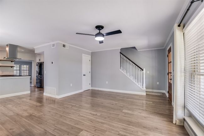 Unfurnished living room featuring ceiling fan, stairs, ornamental molding, and light wood-style floors | Image 6