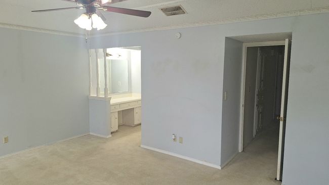 Empty primary bedroom featuring light carpet, a ceiling fan, ornamental molding, and a smoke detector | Image 16