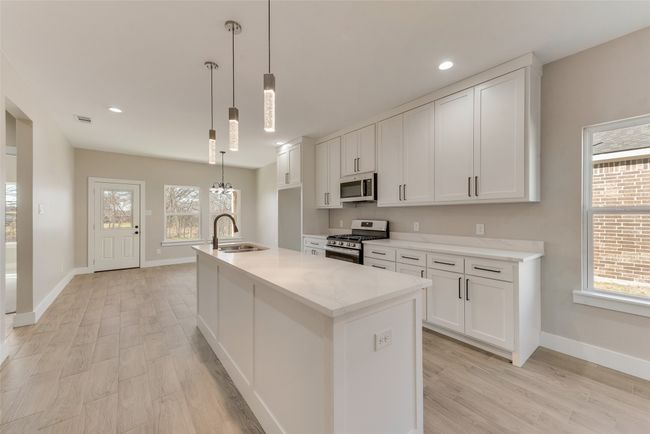 Kitchen with stainless steel appliances, light wood-type flooring, white cabinets, healthy amount of natural light, and recessed lighting | Image 11