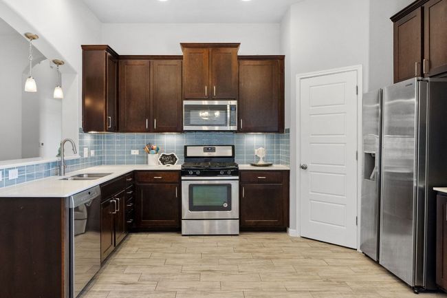 Upgraded ocean-blue glass subway tile backsplash and a gas range | Image 14