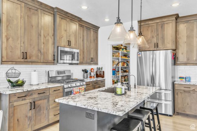 Kitchen featuring stainless steel appliances, tasteful backsplash, a kitchen breakfast bar, light stone counters, and recessed lighting | Image 11
